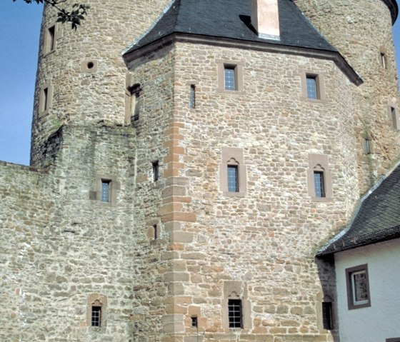 Le château de Bertrada à Mürlenbach présente deux tours rondes et un arc de porte en pierre sous un ciel bleu et clair., © TI Bitburger Land Le château de Bertrada à Mürlenbach présente deux tours rondes et un arc de porte en pierre sous un ciel bleu et clair., © TI Bitburger Land