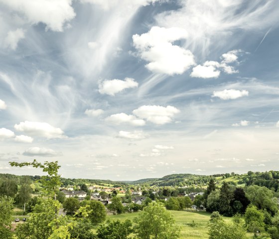 Paysage vert avec des champs, des arbres et un village. Le ciel est bleu avec des nuages blancs qui s'étendent sur la scène., © Eifel Tourismus, Dominik Ketz Paysage vert avec des champs, des arbres et un village. Le ciel est bleu avec des nuages blancs qui s'étendent sur la scène., © Eifel Tourismus, Dominik Ketz