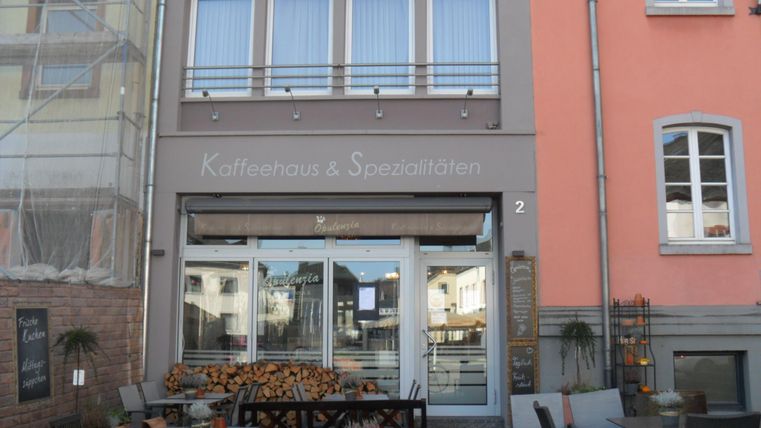 A cozy café with outdoor tables. Above the door, it says "Coffee House & Specialties".