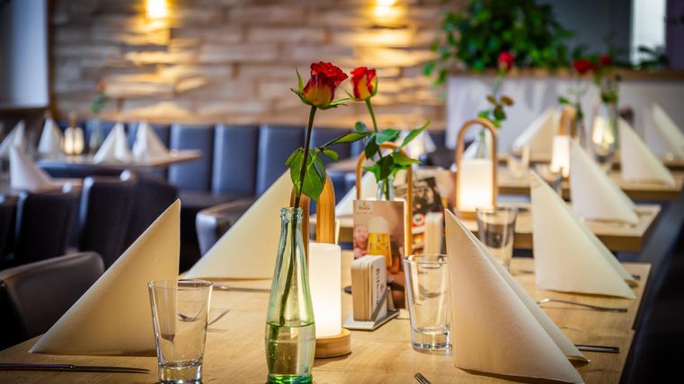 An elegant restaurant with beautifully set tables. Each table has red roses and decorative place cards.