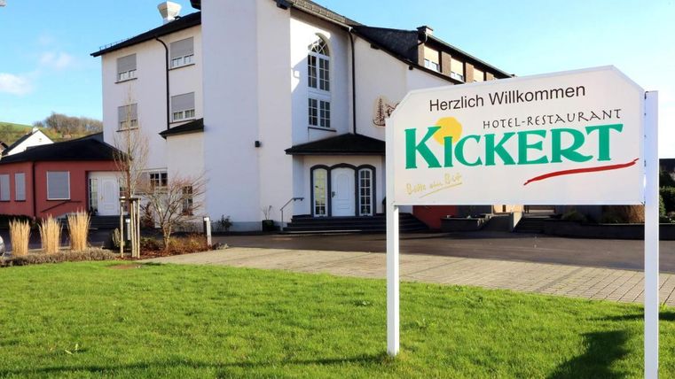 An inviting hotel-restaurant named "Kickert". The facade is modern and surrounded by green grass.