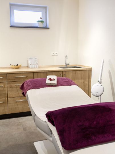 A cozy treatment room with a reclining chair and wooden shelves. The color scheme is bright and inviting.