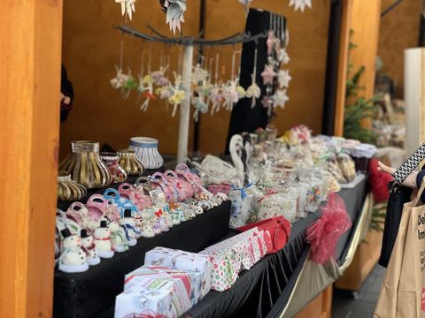 Un stand de marché coloré avec différents articles de décoration faits main.
Il y a beaucoup de bonbons et de petits cadeaux proposés à la vente.