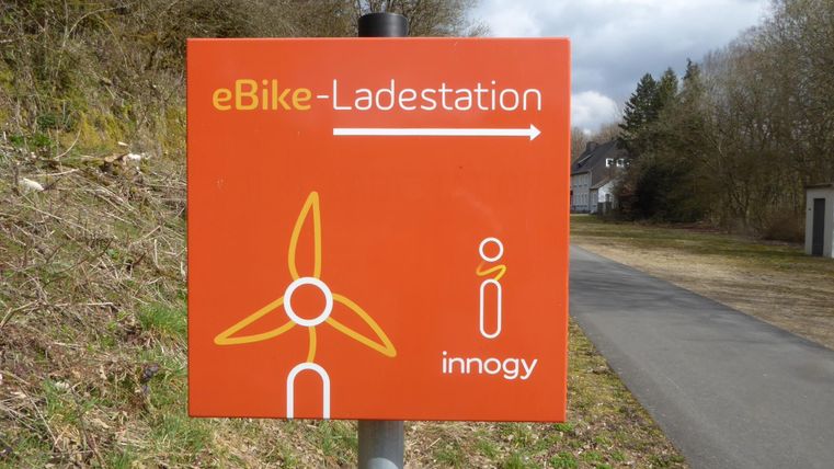 An orange hint for an eBike charging station with a wind turbine symbol. The charging station is located in the direction of the displayed arrow.