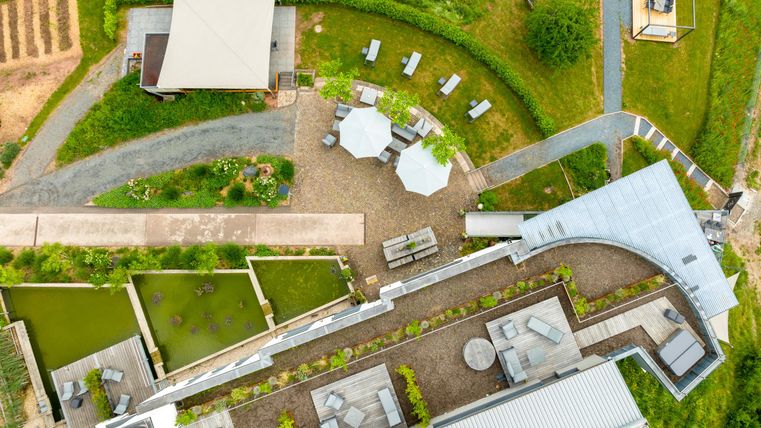 A modern garden landscape with seating areas and paths. The area includes plants, water features, and a large terrace.