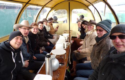 Eine Gruppe von Personen sitzt gemütlich in einem geschützten Raum. Sie trinken etwas und genießen die Gesellschaft.