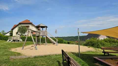 Zandspeelplaats met houten kindertorens en een grote zandbak met zonnescherm.