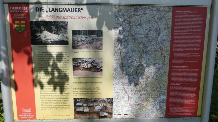 An information board about the "Langmauer" with images and a map. The board is located in a green environment and provides historical information.