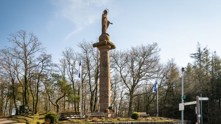 Marian column near Waxweiler with blue sky and trees in the background.