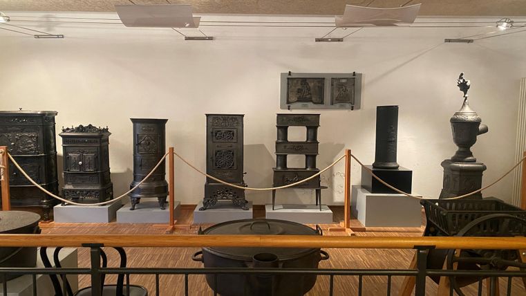 Een tentoonstelling met antieke kachels en radiatoren in een museumshow. De objecten zijn op sokkels geplaatst en beveiligd met een afzetting.