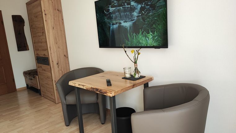 A modern room with two comfortable chairs and a small table. A TV hangs on the wall, displaying an impressive nature shot.