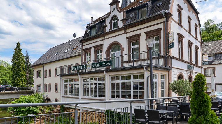 A charming building that houses a pizzeria. Outside there are seating areas and a beautiful view of the surroundings.