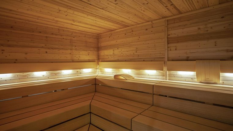 A modern sauna with wooden paneling and soft lighting. The room radiates warmth and relaxation.