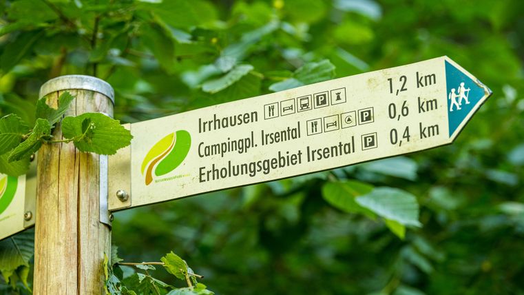 Auf einem Schild in Pfeil-Form sind die Entfernungen zum nächsten Wanderziel angegeben