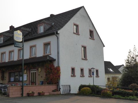 A two-story house with a simple exterior and an inviting entrance area. In front of the house, there are small flowerbeds and a quiet street.