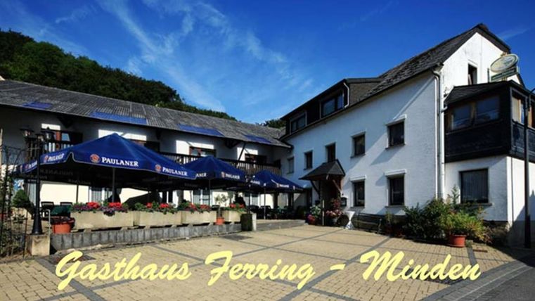 An inviting inn with a beautiful outdoor area and tables under sunshades. The façade is friendly and bright in a peaceful environment.