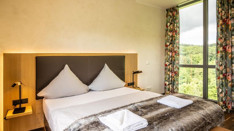 A modern bedroom with a large bed and elegant bed linen.
Large windows overlooking the green landscape provide plenty of daylight.