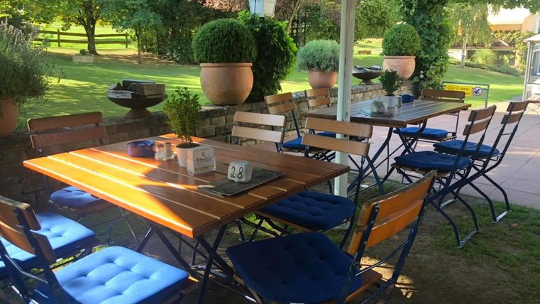 An inviting outdoor area with a table and chairs. In the background, green trees and plants can be seen.