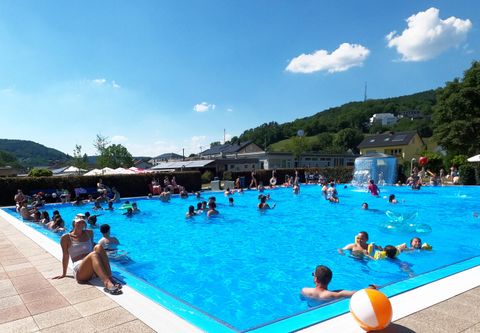 Ein belebter Swimmingpool an einem sonnigen Tag. Viele Menschen genießen das Wasser und die entspannte Atmosphäre.