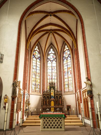 An impressive church with high vaults and colorful windows. The altar area is centrally and elaborately designed.