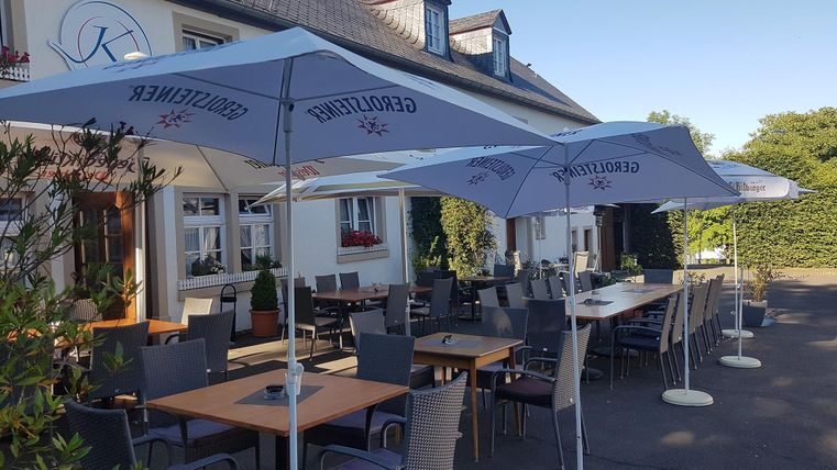 Ein einladendes Restaurant mit einer Außenterrasse. Tische sind mit Sonnenschirmen versehen und befinden sich in einem ruhigen Umfeld.