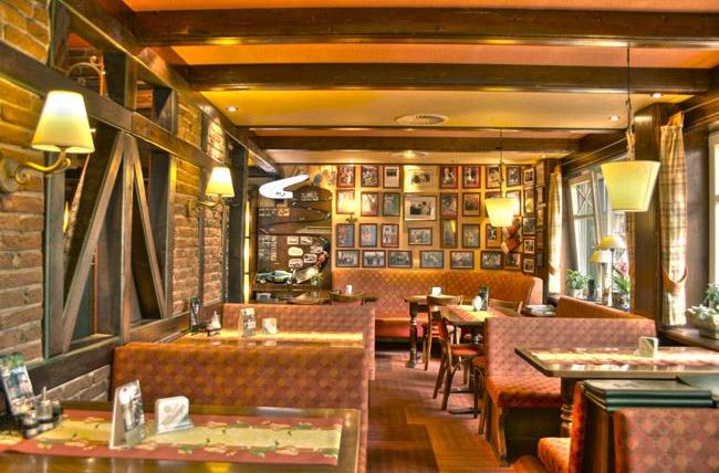 A cozy restaurant with rustic interior and warm lighting. Numerous pictures hang on the walls, creating an inviting atmosphere.