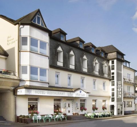 Een charmant hotel met restaurant, dat een uitnodigende gevel en grote ramen heeft. Er zijn zitgelegenheden buiten en een rustige omgeving.