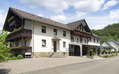 Ein modernes Gebäude mit mehreren Etagen und Balkonen. Umgeben von Bäumen und einem klaren Himmel.