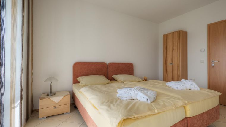 Ein gemütliches Schlafzimmer mit zwei Einzelbetten und gelben Bettbezügen. Die Wände sind hell und die Einrichtung ist modern und schlicht.