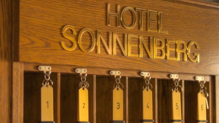 Ein eleganter Empfangsbereich des Hotels Sonnenberg mit schlichten Schlüsselanhängern. Die Holztäfelung verleiht dem Raum einen warmen und einladenden Charakter.