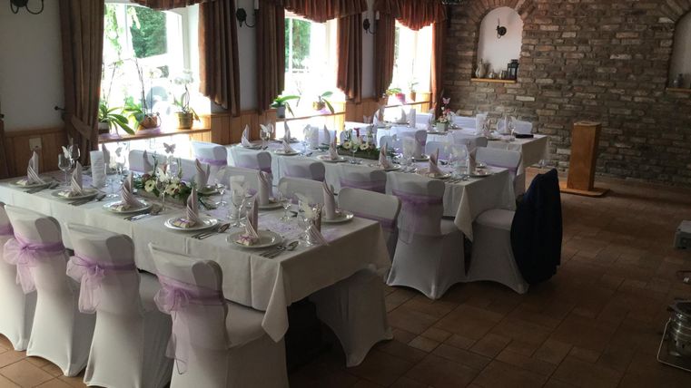 An elegant hall with festively set tables and chairs. The windows let in plenty of daylight and create a friendly atmosphere.