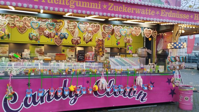 A colorful candy stand with many treats. Here you can find hearts, cotton candy, and other snacks.