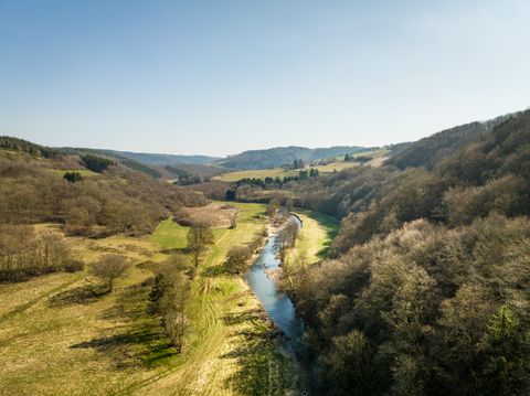 Landscape with river, meadows and hills under a blue sky.