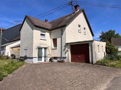 Een groot, licht huis met een rood garagedeur en tuin. Het gebouw heeft een heldere, moderne stijl en is omgeven door groenvoorzieningen.