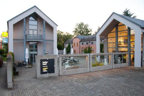 A modern building with two separate entrances and large windows. The outdoor area is equipped with tables and sun umbrellas, perfect for a relaxed atmosphere.