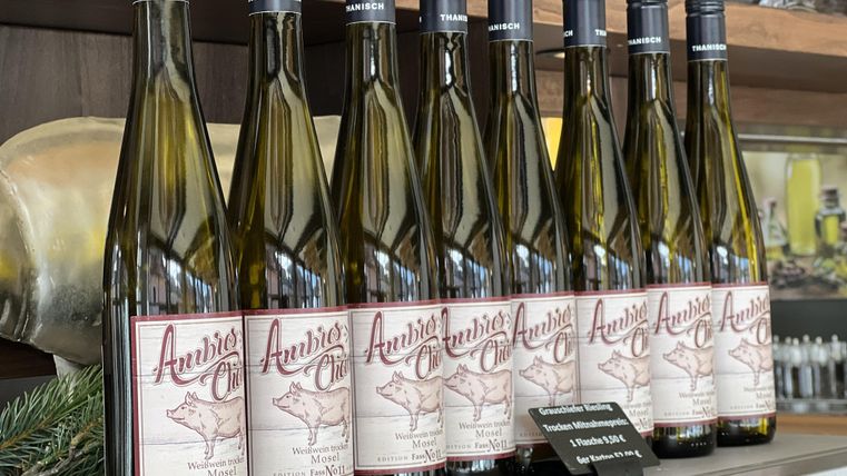 A row of wine bottles is standing on a shelf. The bottles have a decorative label featuring a stylized deer.