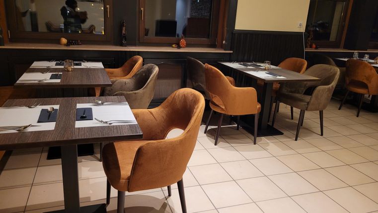 Een elegant restaurant met mooi gedekte tafels en moderne, comfortabele stoelen. De sfeer is uitnodigend en gezellig.