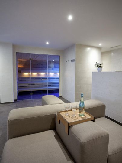 A modern living room with a comfortable sofa and a small table. A gentle light is visible through the windows.