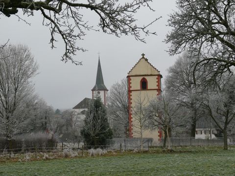 Un paysage enneigé avec deux églises et des arbres gelés. Le ciel est gris et nuageux.