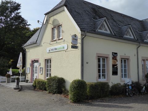 A charming building with a yellow facade and a sign on the wall. Bicycles are parked in front of the house, and a small outdoor area with tables is visible.