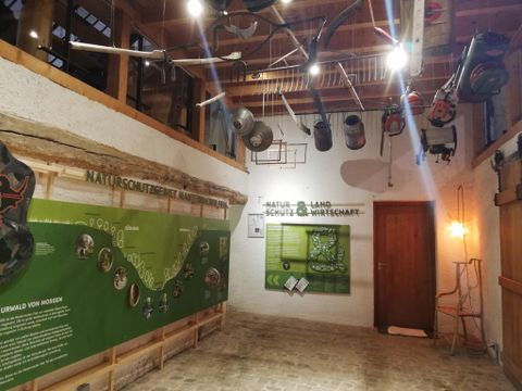 Een interieur met een informatieve wanddecoratie over natuurbescherming. Verschillende apparaten hangen aan het plafond en er zijn groene elementen op de muren.