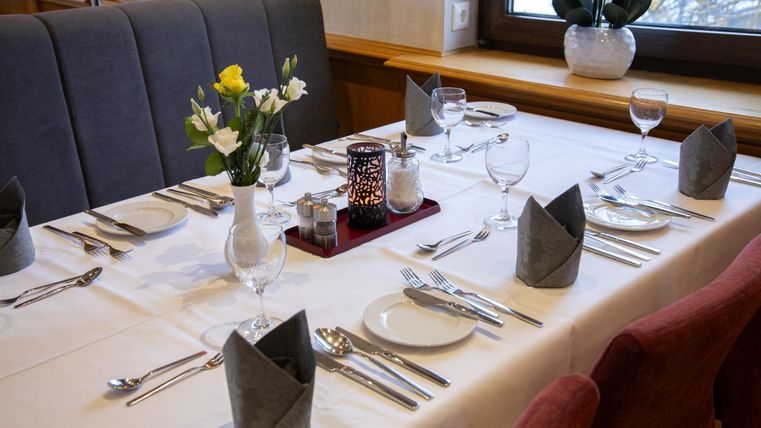 An elegantly set table with cutlery, glasses, and flowers. The decor is modern and inviting.
