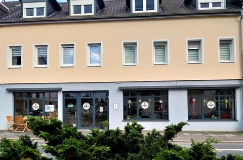 A modern office building with a bright facade. In front of the building, there are some furnishings and large windows with inviting signs.