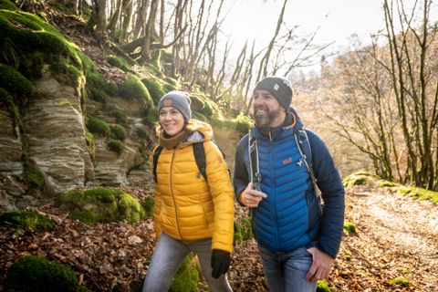 Deux randonneurs sur un joli sentier forestier avec de la mousse verte et des rochers. Il semble qu'il fasse un jour ensoleillé et la nature autour d'eux est vivante.