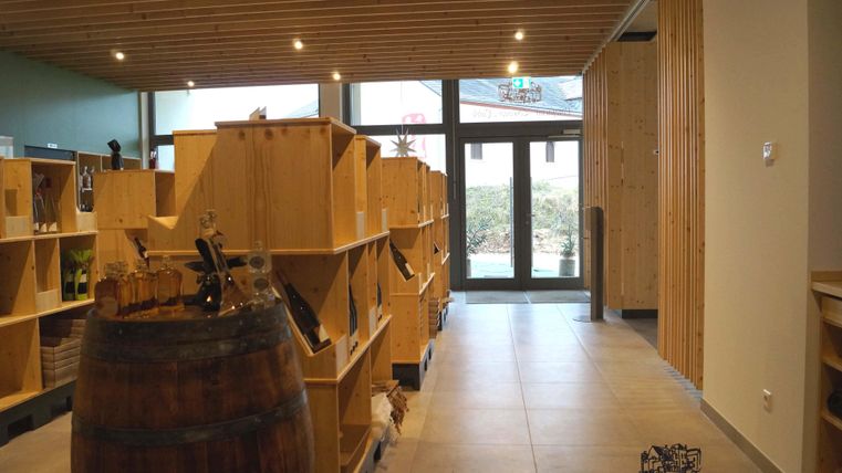 A modern store with wooden shelves and an open atmosphere. In the background, large windows overlook an outdoor area.