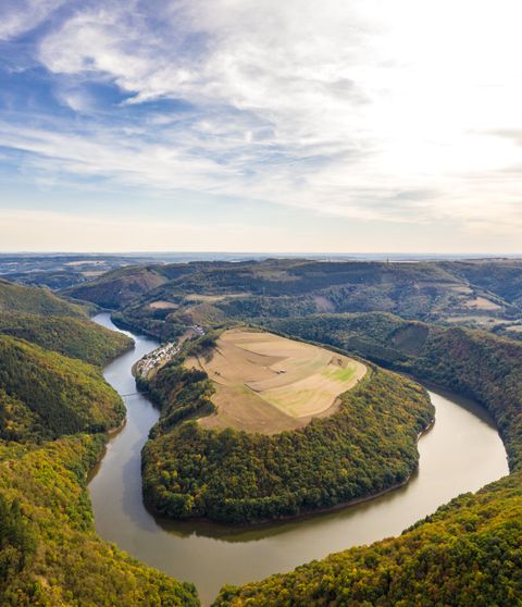 Luftaufnahme einer Flusslandschaft mit bewaldeten Hügeln und Feldern.