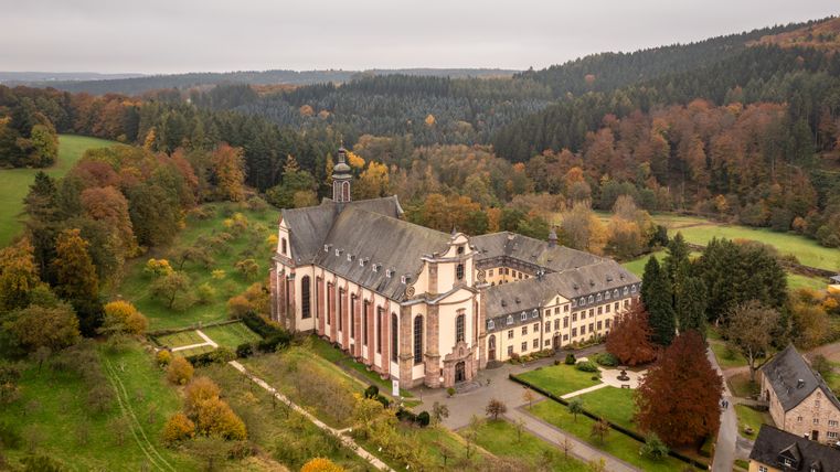 Luftaufnahme des Klosters Himmerod umgeben von herbstlichen Wäldern.
