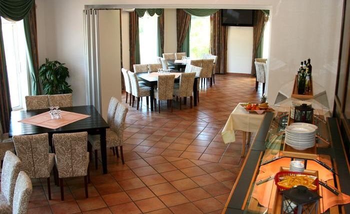 A cozy restaurant with bright chairs and a large room. The floor is tiled and there is a buffet area.