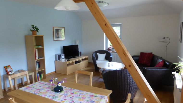 A bright living room with wooden furniture and a large dining table. The cozy sitting area invites you to relax.