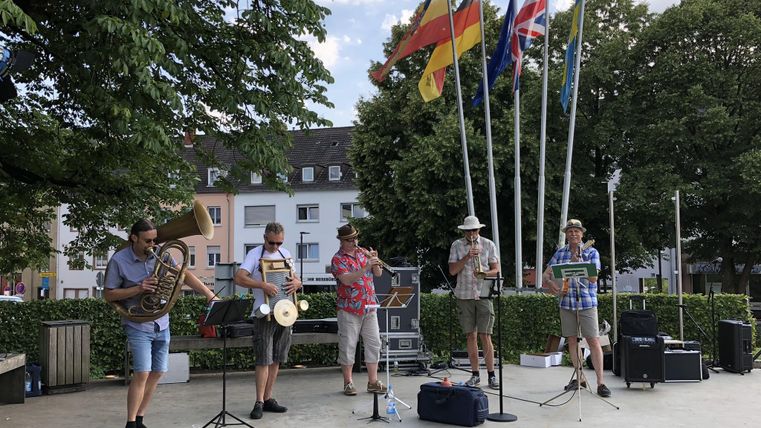A music group is playing outdoors. Several flags can be seen in the background.